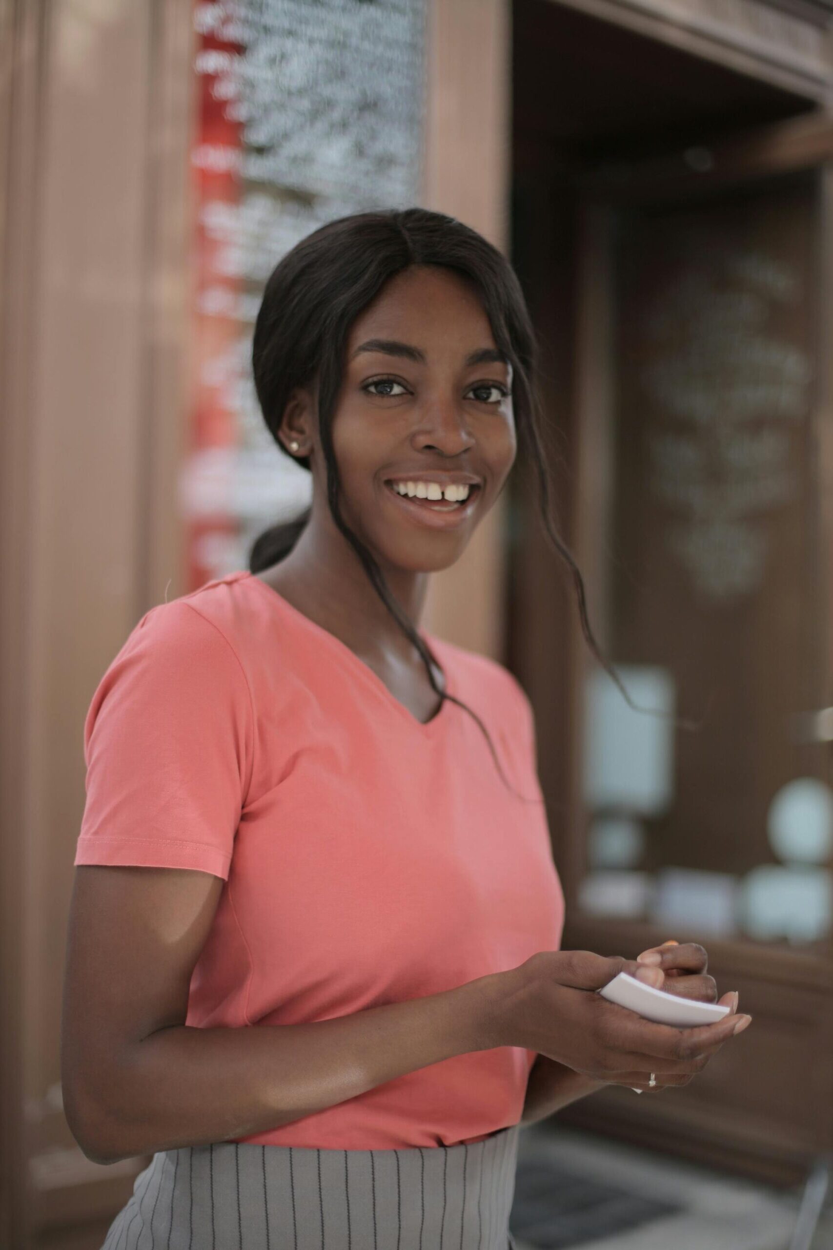 Young woman smiling while taking notes indoors at a cafe.